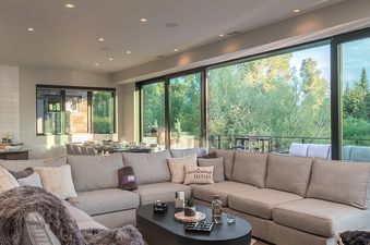 The open concept living area seamlessly blends a spacious lounge, dining area, and kitchen, all bathed in natural light from expansive windows that offer stunning views of the lush green landscape.