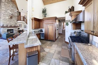 A kitchen with stainless steel appliances, granite countertops, a fireplace, and a large window.