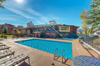 The outdoor pool area at Phoenix offers a large swimming pool, hot tubs, and lounge chairs surrounded by a fence and building.