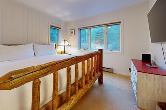 Cozy bedroom in Teewinot C3 with a rustic log bed and forest views.