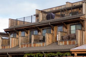 The exterior of Cana Loft 301 features multiple wooden balconies and a rooftop deck with a barbecue grill.
