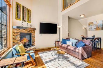 A living room with a fireplace, a large TV, a leather sofa, and a blue armchair.