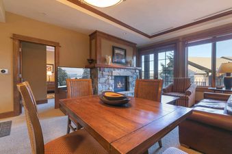 A cozy living room with a stone fireplace and a large window with a view of the mountains.