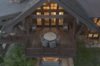 An aerial view of the Martin Creek Cottage's multi-level outdoor living space, featuring a dining deck and a lower patio area.