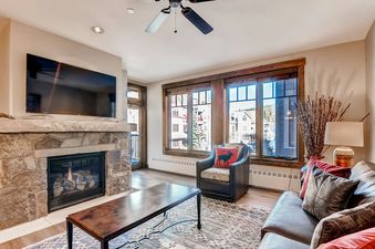 A living room with a fireplace, large windows, and a leather couch