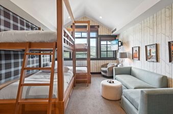 A bunk room in Flagstaff 507 with four beds, a lounge area, a TV, and a window overlooking mountains.
