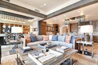 A modern open-concept living space in the Silver Strike Lodge 602 Presidential Suite featuring a large sectional sofa, wooden coffee table, and an adjoining kitchen and dining area.