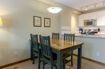 A dining table with four chairs sits in a cozy dining area, adjacent to a compact and functional kitchen.