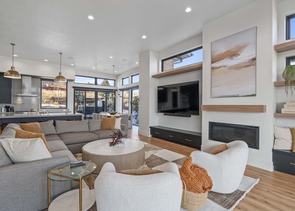 A modern living room with a large sectional sofa, a fireplace, and a flat screen TV.
