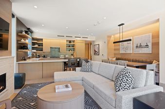 An inviting open-concept living area in Assay Hill Lodge Unit 264 features a modern kitchen, dining nook, and a comfortable lounge with a fireplace.