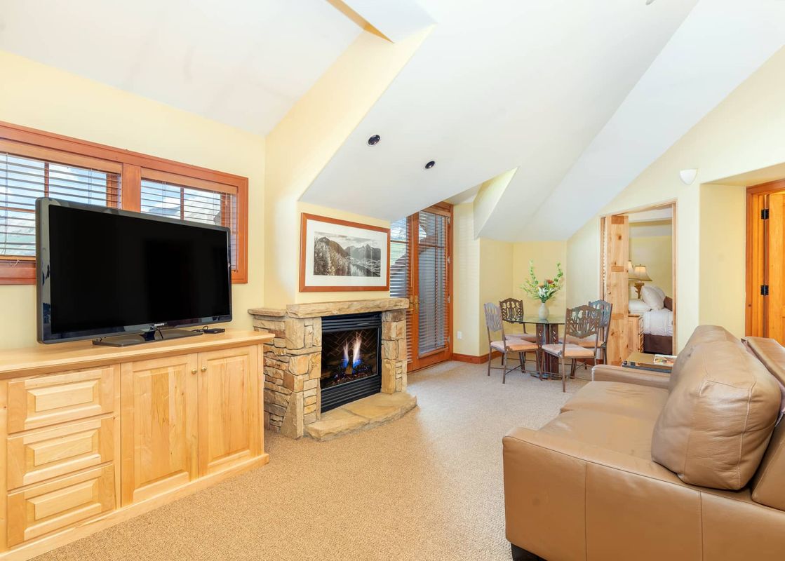 The living room of Lost Creek Two Bedroom Condo features a fireplace, a large flat-screen TV, and a brown leather sofa.