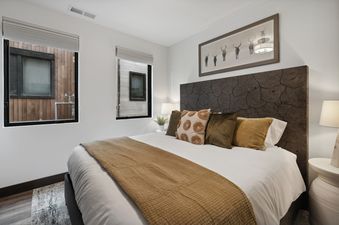 A cozy bedroom at Huckleberry Haven with a bed, wood-slice headboard, and warm lighting from bedside lamps.