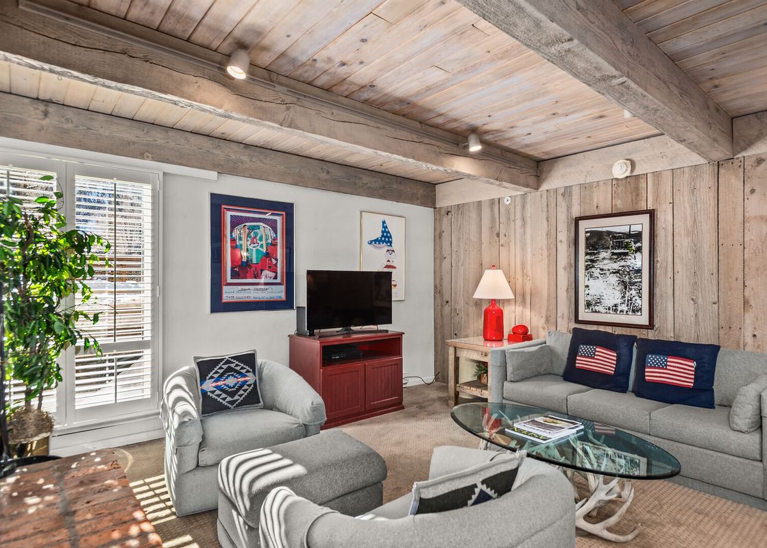 The cozy living room at Chateau Eau Claire Unit 1 features wood paneled walls and ceiling.