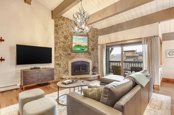 The inviting living area of the Phoenix 120 features a comfortable sofa, a large TV, and a stone fireplace, creating a cozy and entertainment-ready space.