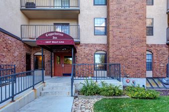 The welcoming entrance of the Copperbottom Inn features a red awning over double brown doors, surrounded by red brick and accessible via steps and a ramp.