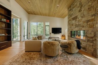 A spacious living room featuring a cozy fireplace, comfortable seating, and large windows that offer views of the surrounding nature.