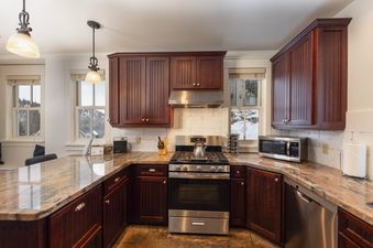 A modern kitchen with dark wood cabinets, stainless steel appliances, and granite countertops.