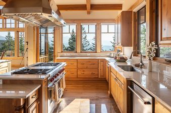 Bright gourmet kitchen at Hitch Haven 3041 with wooden cabinetry, stainless steel appliances, and large windows showcasing mountain views.