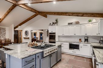 The Lodge at Ski Hill kitchen is spacious, with a large island featuring a stove, light-colored granite countertops, and modern appliances.