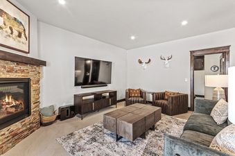 A living room with a fireplace, a television, and a couch. The fireplace has a fire going in it.