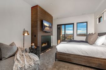 A comfortable bedroom at Abode at Viridian features a fireplace and a balcony with a scenic view.