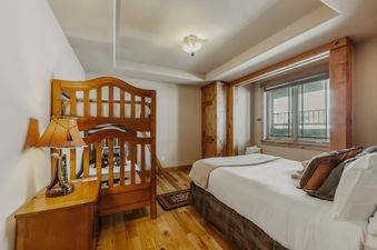 A cozy bedroom features a wooden bunk bed and a comfortable single bed.