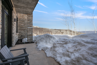 A view of a patio with snow-covered ground and a mountain view in the distance.