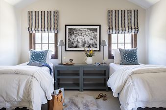 A cozy bedroom with two twin beds, grey bedside tables, and framed artwork, creating a serene and inviting atmosphere.