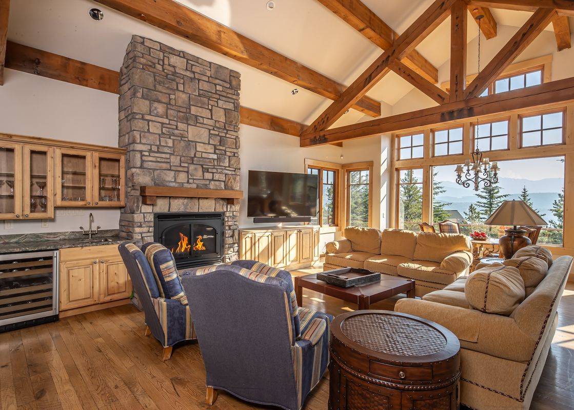 Luxurious open-concept living room at Hitch Haven 3041 with high timber-framed ceilings and a large stone fireplace.