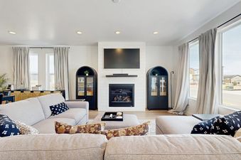 A modern and cozy living room at Silver Creek Retreat featuring a sectional sofa, a fireplace, and large windows.
