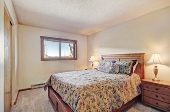 A bedroom with a large window, a double bed, and a wooden nightstand