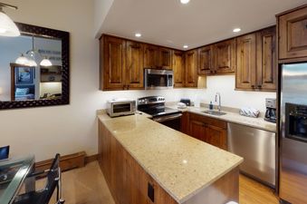 The kitchen in Manor Vail 212 has stainless steel appliances and wood cabinets.