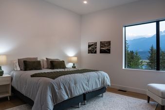 A bedroom with a large window that looks out to a mountain range.