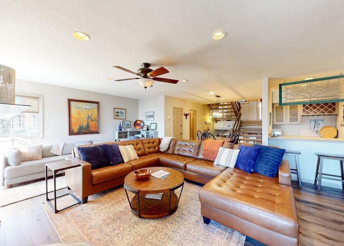 A cozy and spacious living room at La Casa 04 featuring a large leather sectional, wooden coffee table, and an open layout.
