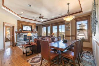 A living room with a fireplace, a large window with a view of the mountains, and a dining table with leather chairs.