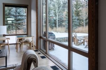 A cozy great room at Lodge at Shooting Star West 01 with large windows overlooking a snowy mountain landscape and inviting armchairs.