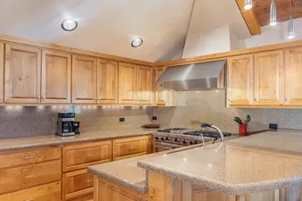 A modern kitchen with wooden cabinets, stainless steel appliances, and a breakfast bar with stools.