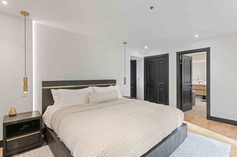 A modern and elegant bedroom in Queen Esther 2366 featuring a king bed with crisp white linens and sleek dark wood accents.