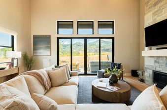 Bright and spacious living room in Mayflower Lakeside 9506 with comfortable seating, a stone fireplace, and scenic mountain views.