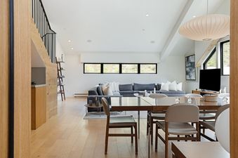 Bright open-concept living and dining area in Tyrolean 6 featuring a grey sectional sofa, modern dining table, and natural light.