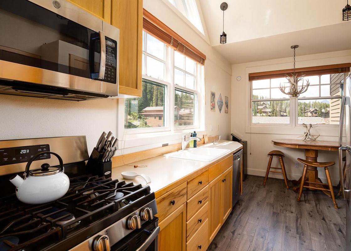 The kitchen in Moonlight Basin Saddle Ridge B5 features stainless steel appliances, wood cabinets, and a view of the mountains.