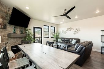 Dining table and living area with black leather sofas and a stone fireplace in Mayflower Lakeside 45-203.