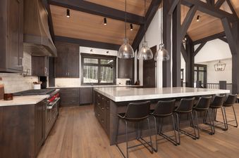 A wide view of the gourmet kitchen at Summit View Chalet Big Sky, featuring dark wood cabinets, light countertops, and a large island with seating.