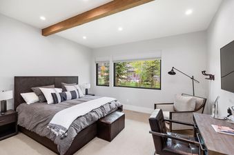 A cozy bedroom with a large bed, dark wood furniture, and a window offering a view of lush trees, perfect for relaxation.