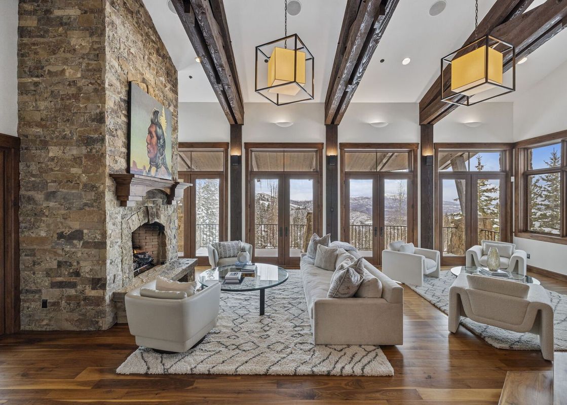 A spacious and inviting living room at Silver Horse at The Colony, featuring a stone fireplace, comfortable seating, and large windows with stunning mountain views.