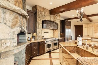 A luxurious kitchen at Park City Colony at Elite Elevation featuring a stone-framed range, granite countertops, and a stone pizza oven.