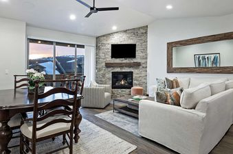 A spacious living room and dining area with a stone fireplace, a large wooden dining table with chairs, and comfortable sofas.