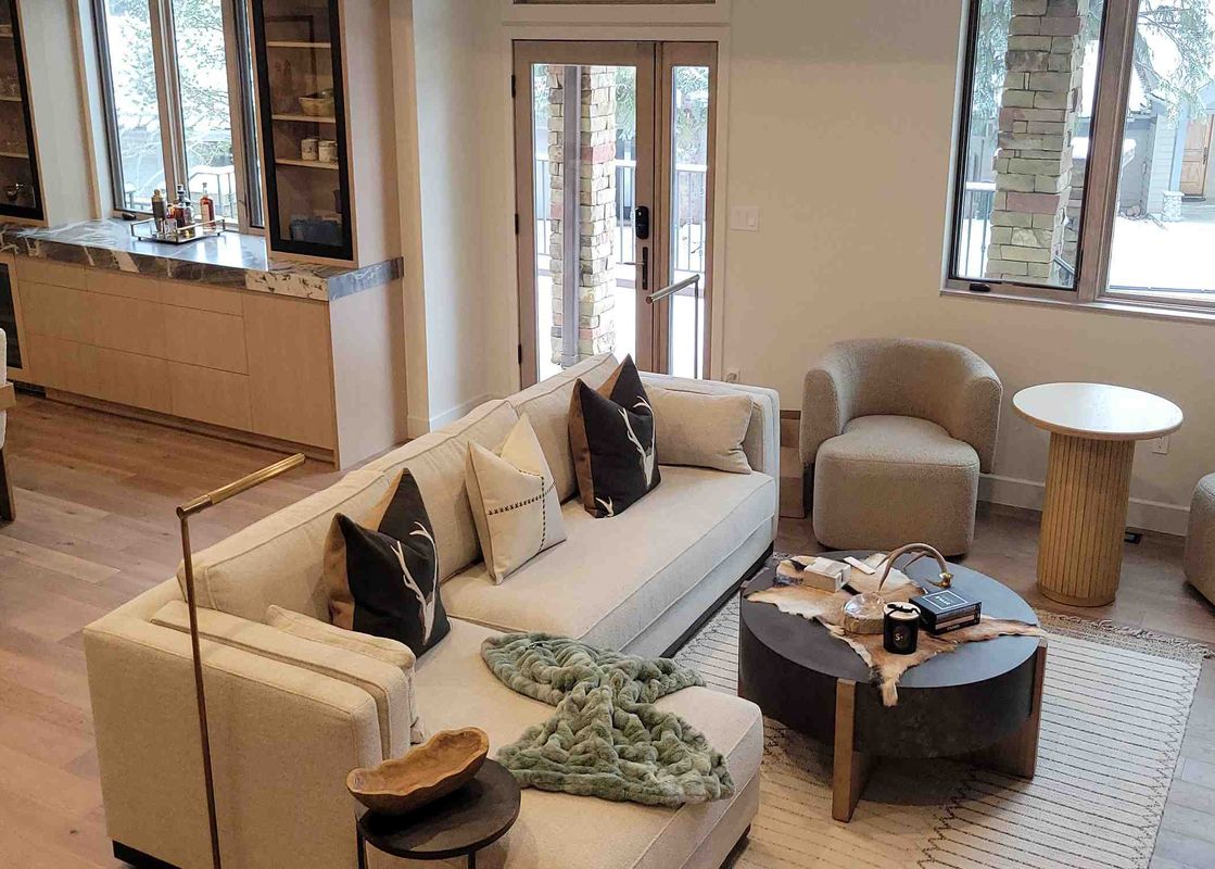 A wide view of the modern open-concept living area at 1175 B Casolar Del Norte, featuring a sectional sofa, armchairs, coffee table, dining area, and a bar.