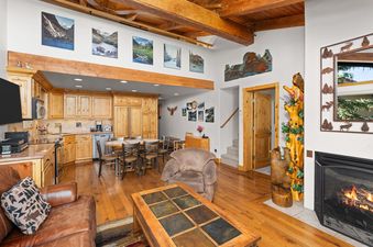 Living area and kitchen of Crestwood 1212 featuring vaulted wood ceilings, a cozy fireplace, and natural wood cabinetry.