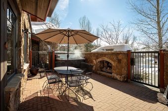 The patio area of Emerald Lodge EL5111 includes a hot tub, outdoor fireplace, and seating area.